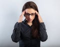 Beautiful serious unhappy concentrated thinking young woman in eyeglasses solving the problem on empty blue studio copy space.