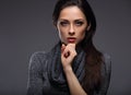 Beautiful serious woman with hand under the face looking concentrated on grey background with empty copy space. Closeup Royalty Free Stock Photo