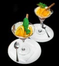 Beautiful serving of scoops of ice cream with slices of orange and mint, ice cream in a glass and saucer with a spoon on a black Royalty Free Stock Photo