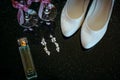 Beautiful set of wedding accessories bride. Morning bride`s. White shoes, pearl earrings, and perfume on a shiny black surface Royalty Free Stock Photo