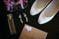 Beautiful set of wedding accessories bride. Morning bride`s. White shoes, pearl earrings, and perfume on a shiny black surface Royalty Free Stock Photo