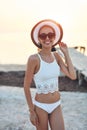 Beautiful sexual woman in white hat and bikini on a wooden pier against the sea and sunset Royalty Free Stock Photo