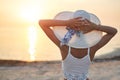 Beautiful sexual woman in white hat and bikini against the sea and sunset Royalty Free Stock Photo