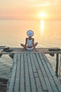 Beautiful sexual woman in white hat and bikini on a wooden pier against the sea and sunset Royalty Free Stock Photo