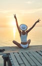 Beautiful sexual woman in white hat and bikini on a wooden pier against the sea and sunset Royalty Free Stock Photo