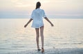 Beautiful sexual woman in white shirt and bikini walking on the beach against the sea and sunset Royalty Free Stock Photo