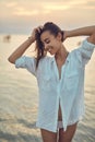 Beautiful sexual woman in white shirt and bikini walking on the beach against the sea and sunset Royalty Free Stock Photo