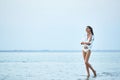 Beautiful sexual woman in white shirt and bikini walking on the beach against the sea and sunset Royalty Free Stock Photo