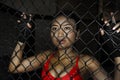 Beautiful and Asian fighter woman in fighting gloves and sport clothes inside MMA cage posing cool Royalty Free Stock Photo