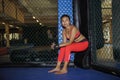 Beautiful and Asian fighter woman in fighting gloves and sport clothes inside MMA cage posing cool Royalty Free Stock Photo