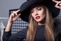 Beautiful attractive girl in a black hat with red lipstick in fashion photography in a black dress with a bright evening make Royalty Free Stock Photo