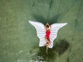 Beautiful and sexy, attractive woman in red swimsuit lays on wing shaped inflatable air mattress floating on water. Royalty Free Stock Photo