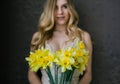 Beautiful blonde woman in beige lingerie with spring flowers bouquet of daffodils. Selective fokus in flowers Royalty Free Stock Photo