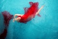 Beautiful sexy blonde young woman swimming with red cloths wrapped in turquoise blue pool water, copy space Royalty Free Stock Photo