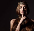 Beautiful brunette beauty woman with long hair wear gold crown and jewellery show tsss sign on dark Royalty Free Stock Photo