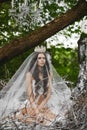 Beautiful and brunette model girl, in lingerie and crown, is sitting in a huge nest in the green forest Royalty Free Stock Photo