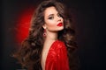 Beautiful sexy brunette in red dress with healthy curly hair and glamour makeup. Fashion Beauty Girl Isolated on black studio Royalty Free Stock Photo