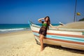 Beautiful sexy brunette on tropical sandy beach near wooden boat on blue sea background and clear sky on hot sunny day Royalty Free Stock Photo