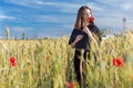 Beautiful cute girl with big lips and red lipstick in a black jacket with a flower poppy standing in a poppy field at sunset Royalty Free Stock Photo