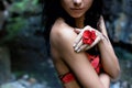 Beautiful cute girl with black hair in a wet bathing suit with a flower in her hair and a ring on his finger in the dark rain Royalty Free Stock Photo