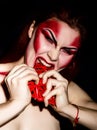 Beautiful devil girl with professional make-up. Fashion Art design. Attractive woman bites the heart