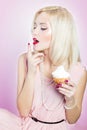 Beautiful elegant blonde woman with bright makeup in pink dress in the Studio on a white background sitting with a cupcake Royalty Free Stock Photo