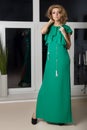 Beautiful elegant long-legged girl in a long green evening dress with evening hairstyle and bright make-up, new year's evenin