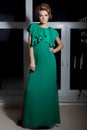 Beautiful elegant long-legged girl in a long green evening dress with evening hairstyle and bright make-up, new year's evenin