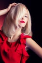 Beautiful elegant striking blonde woman with bright makeup red lips in a red dress in the Studio on a black background