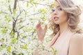 Beautiful elegant sweet blue-eyed blonde girl in the garden near the cherry blossoms on a sunny bright day