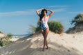 A beautiful European woman with tanned skin walks along the white sandy beach, wears a trendy indoor swimsuit Royalty Free Stock Photo