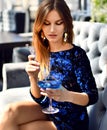 Beautiful fashion brunette woman in expensive interior restaurant drinking drinking blue margarita cocktail on sunset Royalty Free Stock Photo