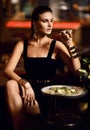 Beautiful fashion brunette woman in expensive interior restaurant eat oyster and lick one finger Royalty Free Stock Photo