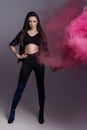 Beautiful fashionable girl in black clothes in a cool shot in the studio with colored pink smoke Royalty Free Stock Photo