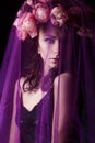 Beautiful girl with black hair in a black lace dress with a wreath on his head covered with a violet veil in the Studio