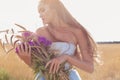 Beautiful girl in a blue dress with long hair , holding a bouquet of ears and pink flowers stands in a field with rye sun at Royalty Free Stock Photo