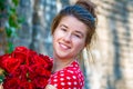 Beautiful and girl with a bouquet of red roses stands on the background of an old brick wall. Royalty Free Stock Photo