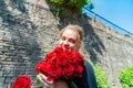 Beautiful and girl with a bouquet of red roses stands on the background of an old brick wall. Royalty Free Stock Photo