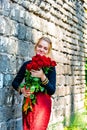 Beautiful and girl with a bouquet of red roses stands on the background of an old brick wall. Royalty Free Stock Photo