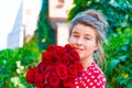 Beautiful and girl with a bouquet of red roses stands on the background of an old brick wall. Royalty Free Stock Photo