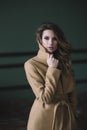 Beautiful sexy girl with curls and full lips in a beige coat in a loft style studio. Beauty and fashion. Soft selective focus