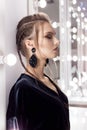 Beautiful girl with hair in the style of rock stands near the mirror in the dressing room in a black velvet gown with a brigh Royalty Free Stock Photo