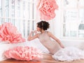 Beautiful girl in a long dress with a huge pink flowers sitting by the window Royalty Free Stock Photo