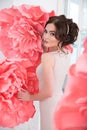 Beautiful girl in a long dress with a huge pink flowers sitting by the window Royalty Free Stock Photo