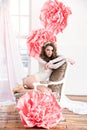 Beautiful girl in a long dress with a huge pink flowers sitting by the window Royalty Free Stock Photo