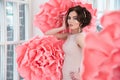 Beautiful girl in a long dress with a huge pink flowers sitting by the window Royalty Free Stock Photo