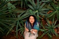 Beautiful sexy girl with multi-colored dreadlocks in a white dress lies on the ground under an orange staircase among the plants,