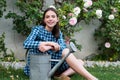 Beautiful sexy girl near rose flower in spring garden. Young woman in flowering garden with roses. Girl gardener with