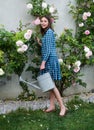 Beautiful sexy girl near rose flower in spring garden. Young woman in flowering garden with roses. Girl gardener with