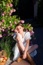 Beautiful sexy girl near rose flower in spring park. Young woman in flowering garden with roses. Beauty model with